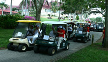 Participants and HMSB VIPs arriving at the golf course in golf buggies.
